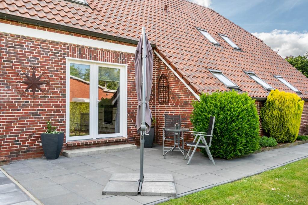 a patio with a table and an umbrella in front of a house at Ferienhaus Behrends in Emden