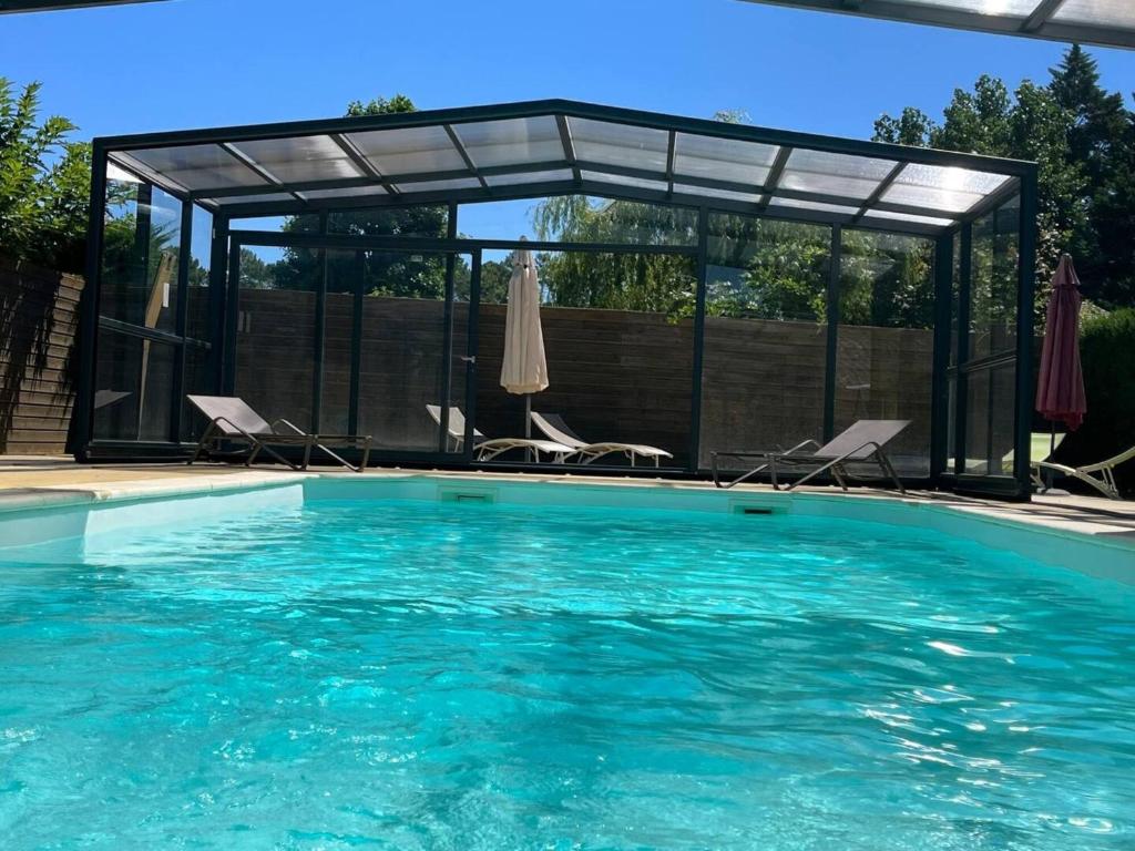 a swimming pool with chairs and a pavilion at Maison La Dune, Piscine et Jardin in Messanges