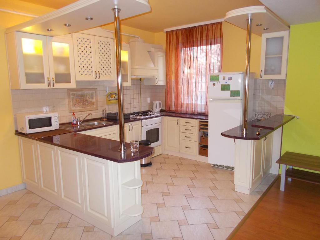 uma cozinha com armários brancos e um frigorífico branco em Lara Apartman em Debrecen
