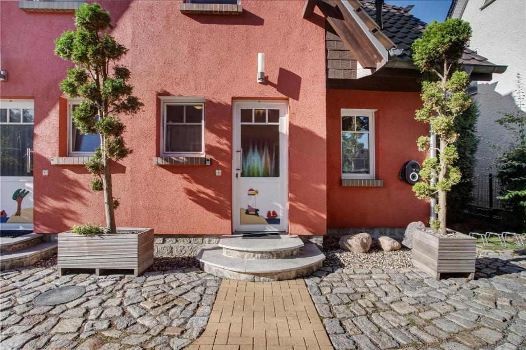 a red house with two trees in front of it at Haus Segelboot Hirtenweg 3c in Zingst