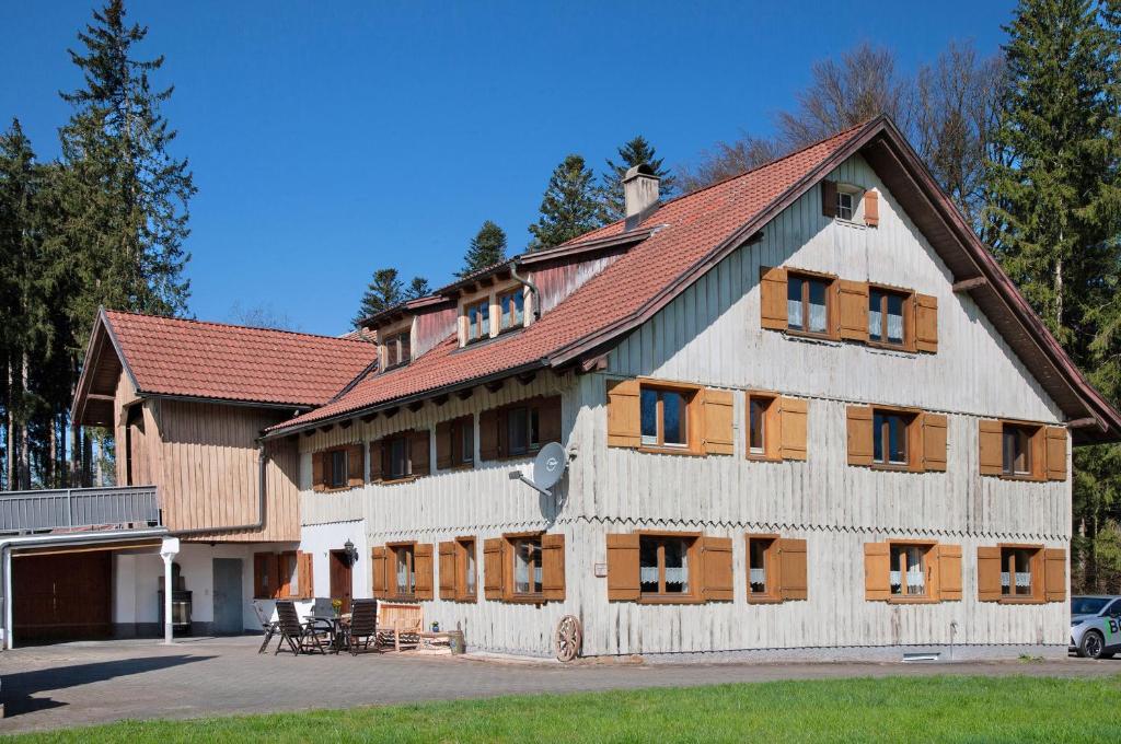a large wooden building with a red roof at Landhaus Moos in Argenbühl