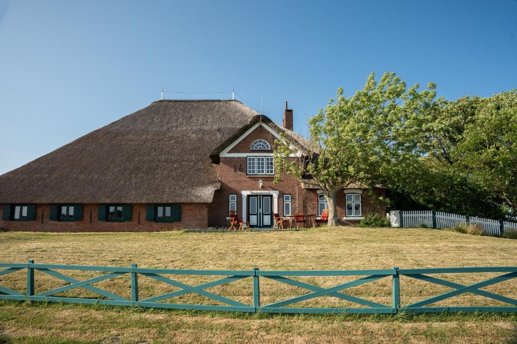 a house with a thatched roof and a fence at Knutzenswarft - Strandläufer in Westerhever