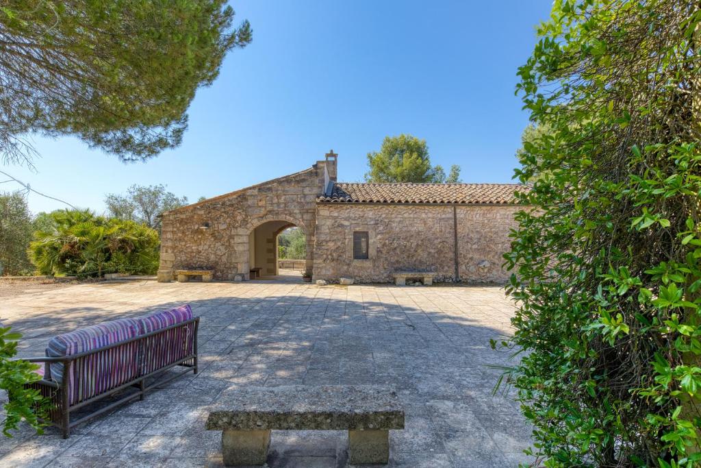 an empty bench in front of a stone building at Tenuta Pizzola in Nociglia
