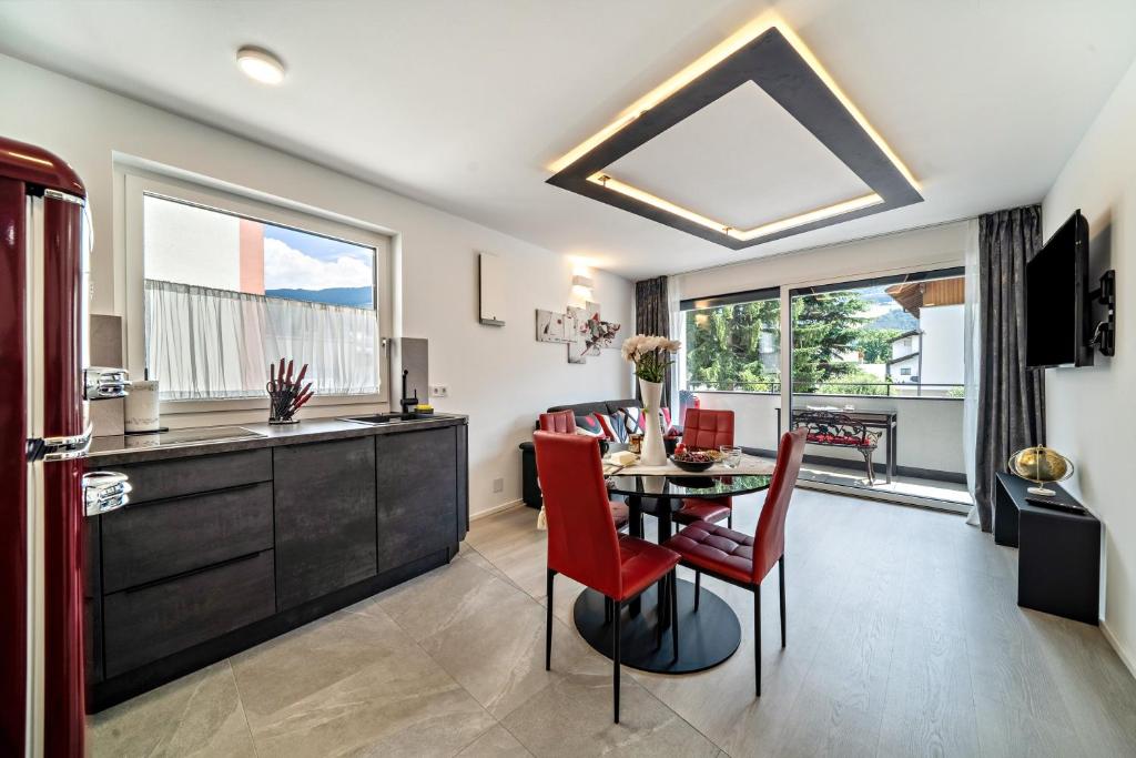 a kitchen and dining room with a table and red chairs at Apartment il cuore rosso in Naturno