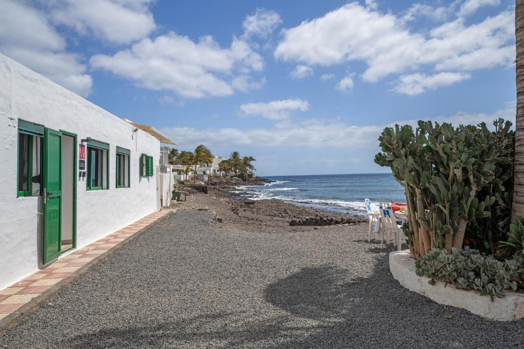 a beach with a white building and the ocean at Apartamentos Callao in Playa Quemada