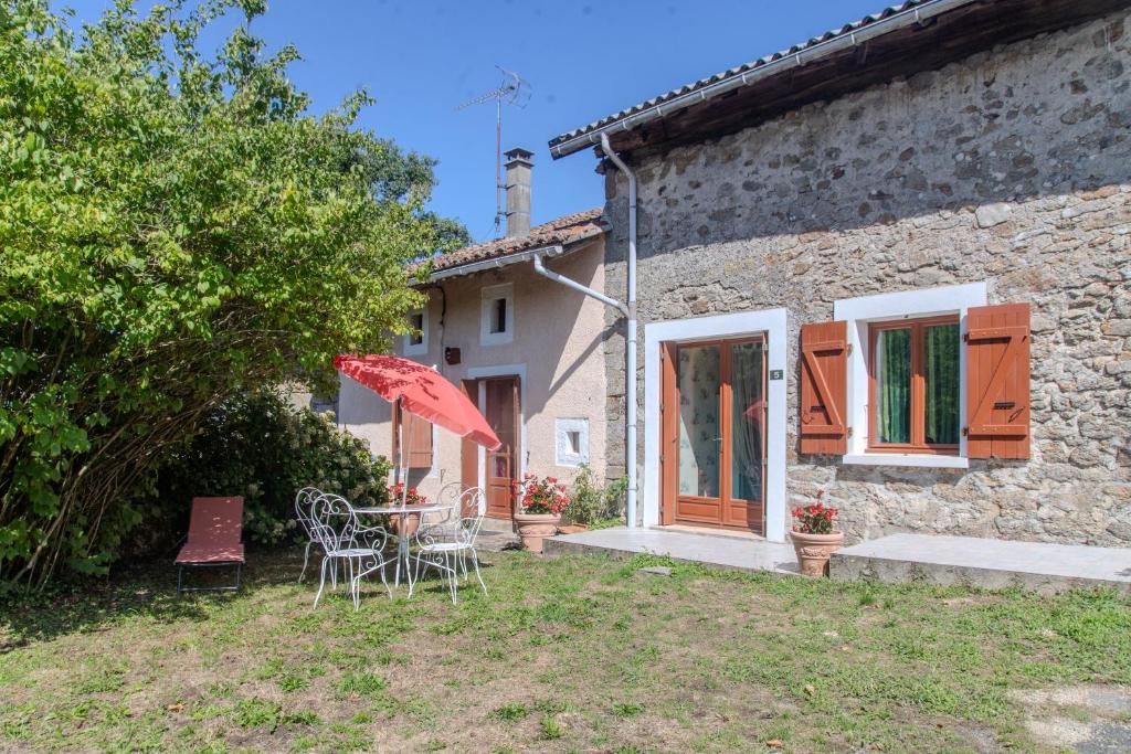 a table and chairs in front of a stone house at Logis des Tilleuls in Saint-Mathieu