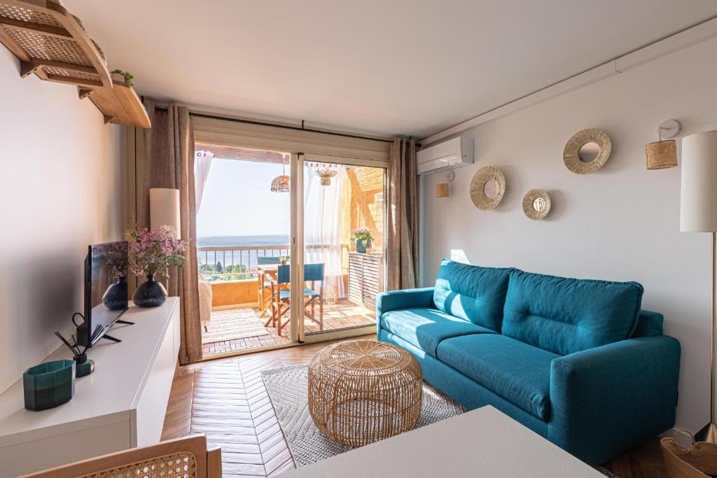 a living room with a blue couch and a balcony at Vue Mer Et Jardin in Théoule-sur-Mer