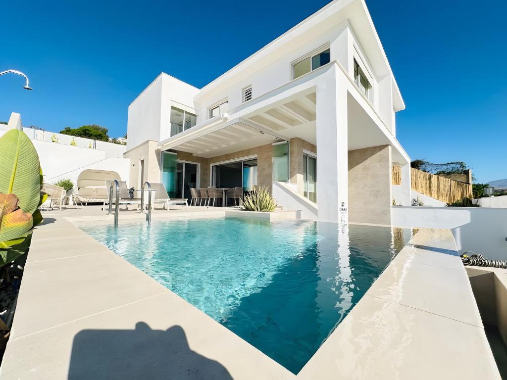 a villa with a swimming pool in front of a house at Casa Blanca in Torre del Mar