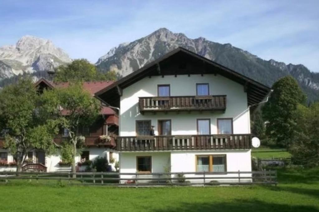 a large white house with a balcony and mountains at Landlhof in Ramsau