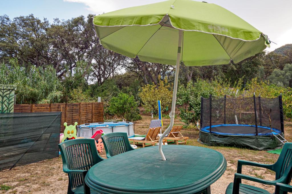 a green table with chairs and an umbrella at Casa Elisa in Padru