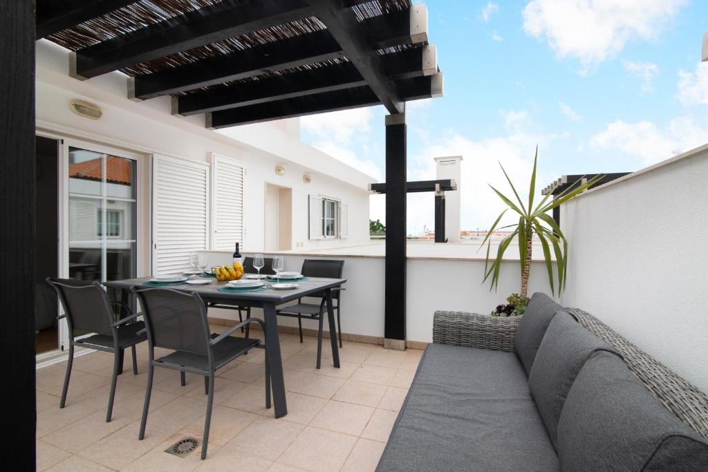 a patio with a table and chairs and a couch at Vista Mar in Cabanas de Tavira