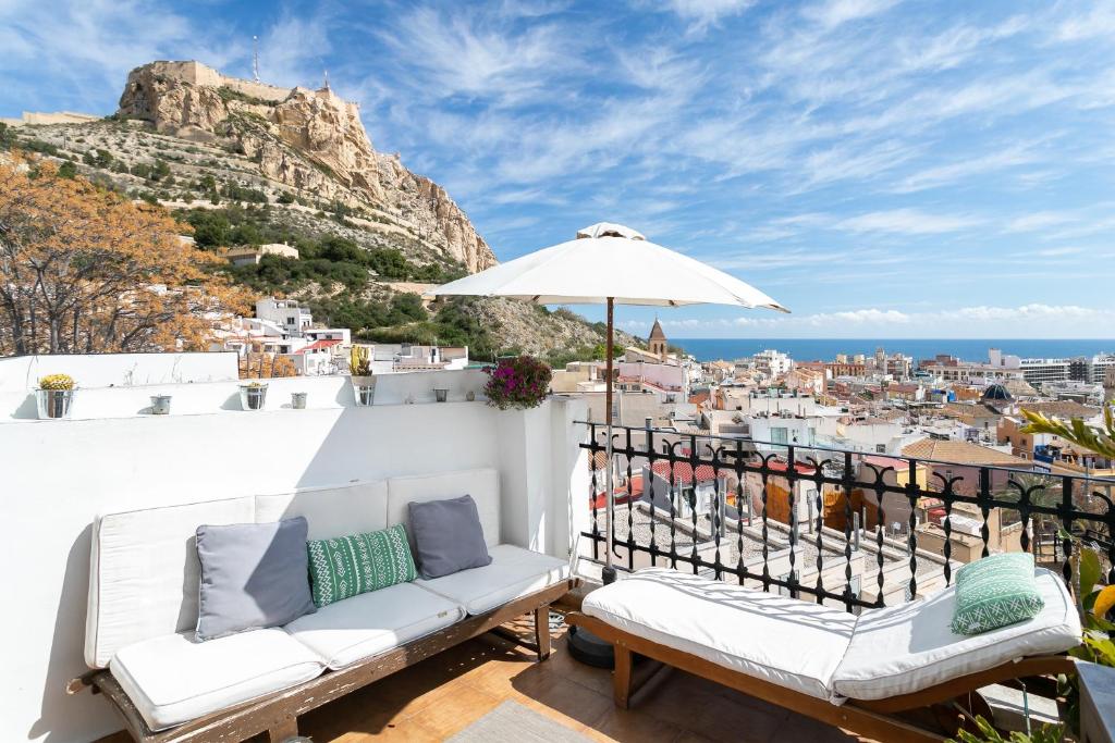 a balcony with two white chairs and an umbrella at Casita Kunterbunt in Alicante