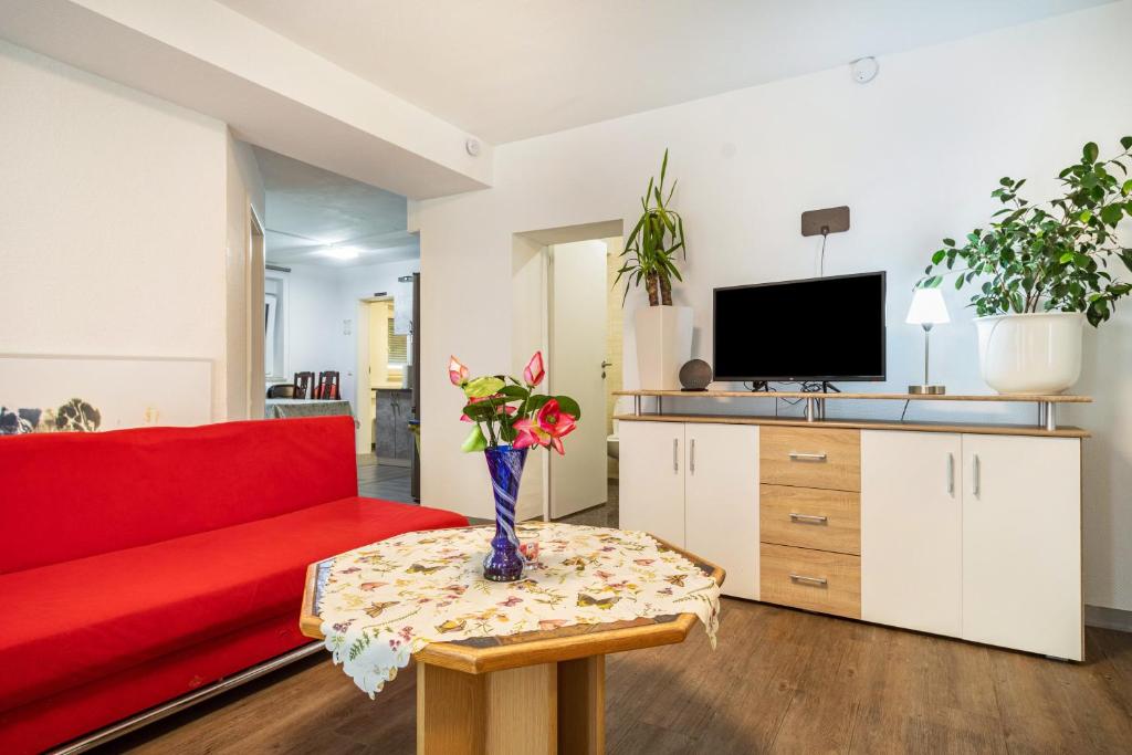 a living room with a red couch and a table with flowers at Nguyen und Le in Neukirch