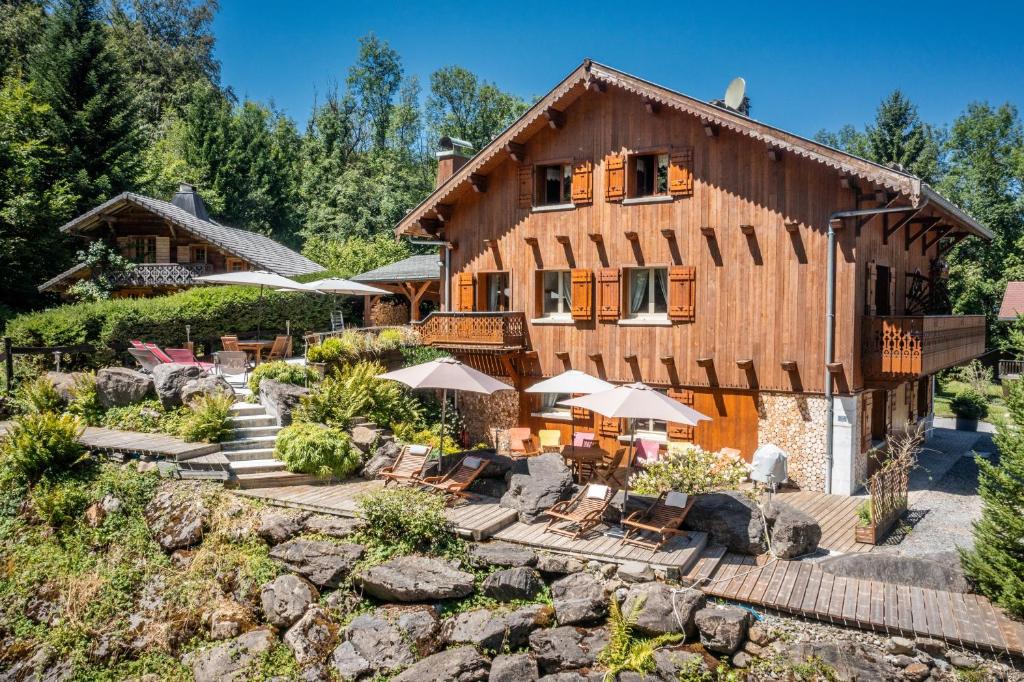 a large wooden house with chairs and umbrellas at Au Rêve Savoyard 1 - 2 personnes in Morillon