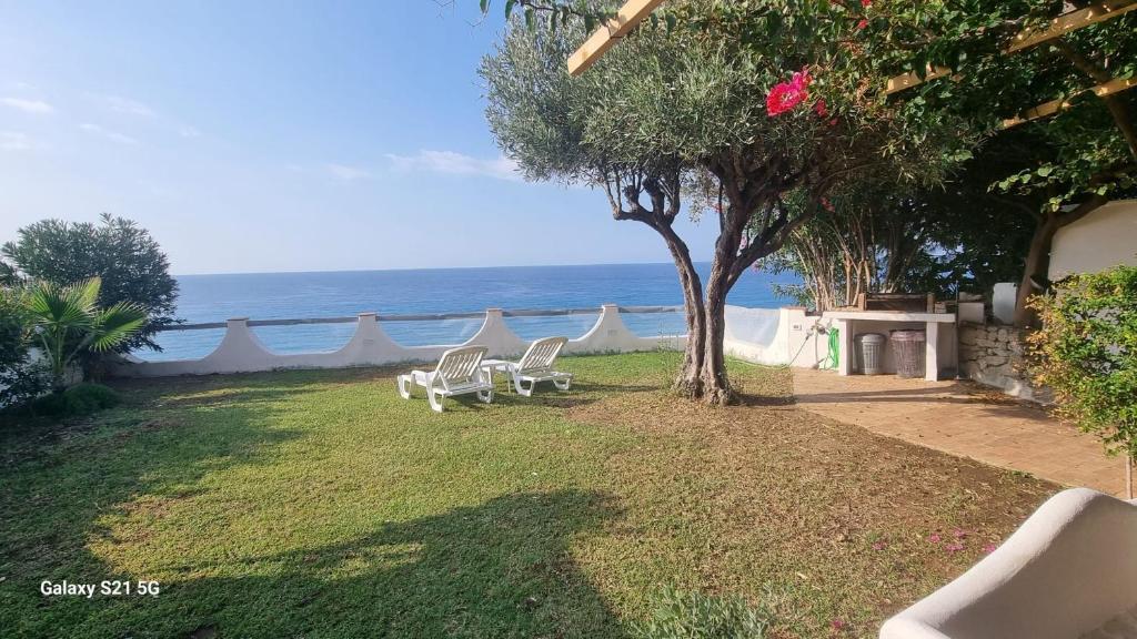 a group of chairs sitting on the grass near the ocean at Costa dei Monaci Villas - Tropea in Parghelia