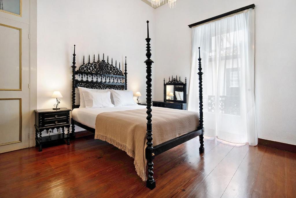 a bedroom with a large bed with a wooden floor at Sé Heritage in Angra do Heroísmo