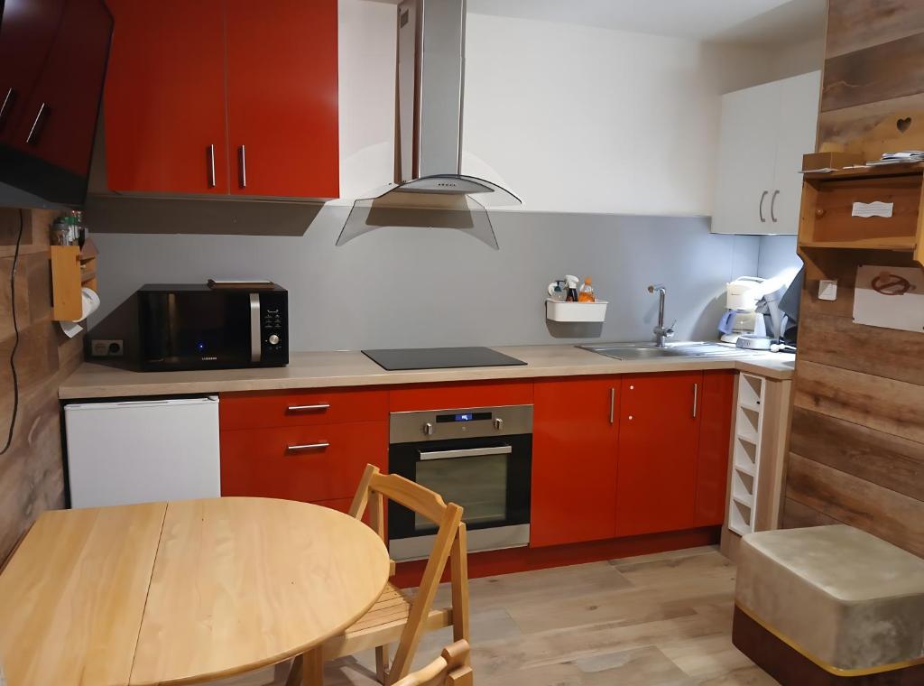 a kitchen with red cabinets and a wooden table at Studio Fontanarosa centre station in Vars