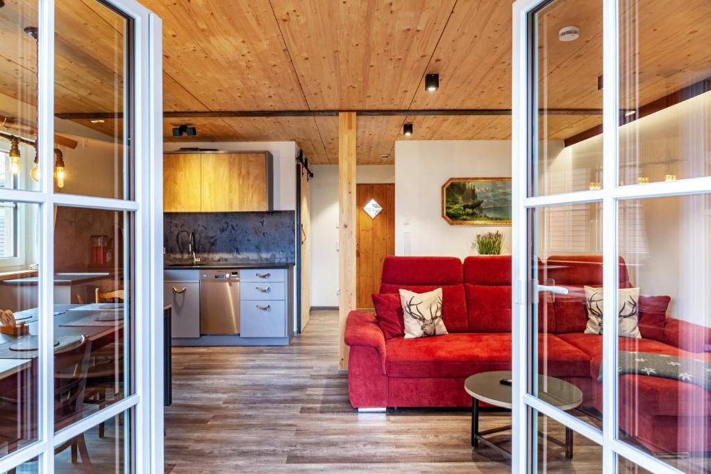 a living room with a red couch and a kitchen at Chalet Rauschn 2 in Farchant