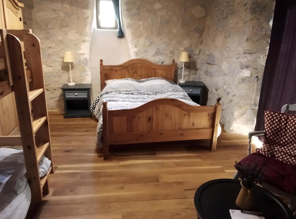 a bedroom with a wooden bed and two night stands at Ferme Des Montagnes Bleues in Bellegarde-en-Diois
