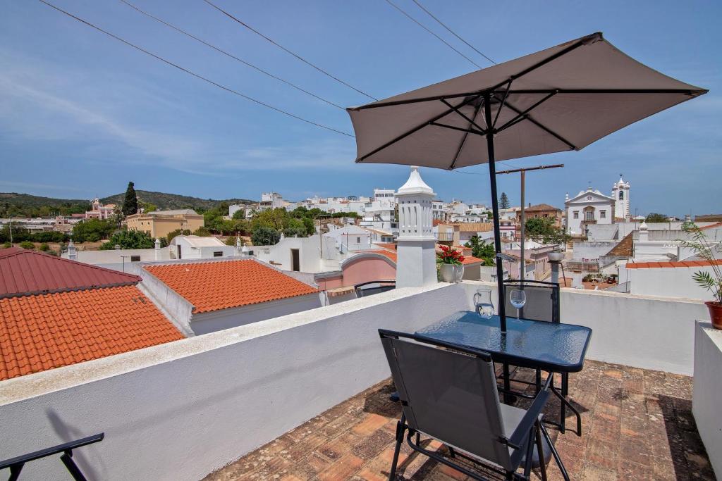 a table and chairs on a balcony with an umbrella at Estoi Heritage in Estói