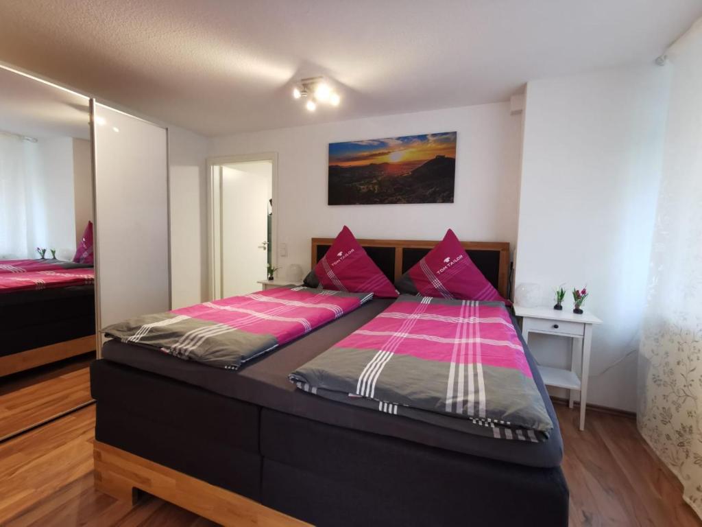a bedroom with a large bed with pink sheets at Ferienwohnung Hogh, 55qm, Terrasse in Beuren