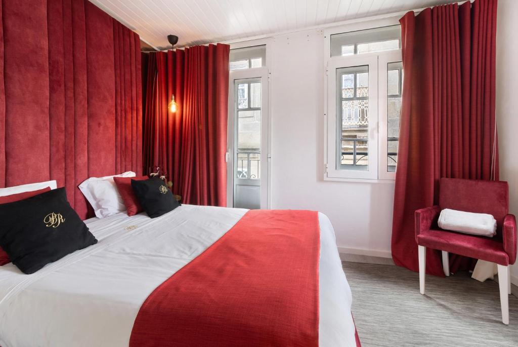a bedroom with red curtains and a bed and a chair at Prestigegoldresidence 2 - Old Town in Guimarães