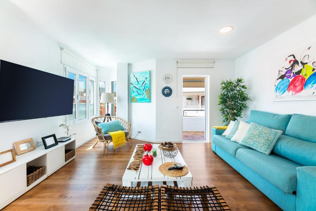 a living room with a blue couch and a tv at Voramar in Pollença