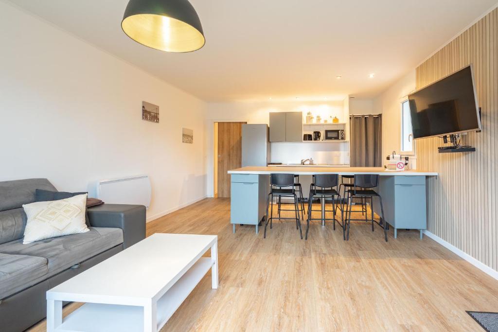 a living room with a couch and a kitchen at L'instant fleuri in Saint-Hippolyte