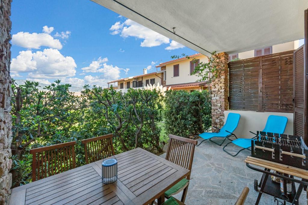 a patio with a wooden table and chairs at Kai Mālie Villasimius in Villasimius