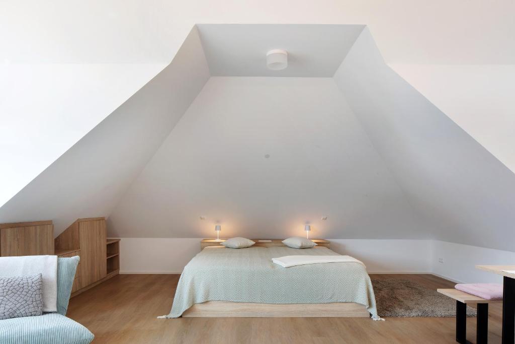 a white attic bedroom with a bed and a chair at Ferienwohnung Hörnleberg in Gutach im Breisgau