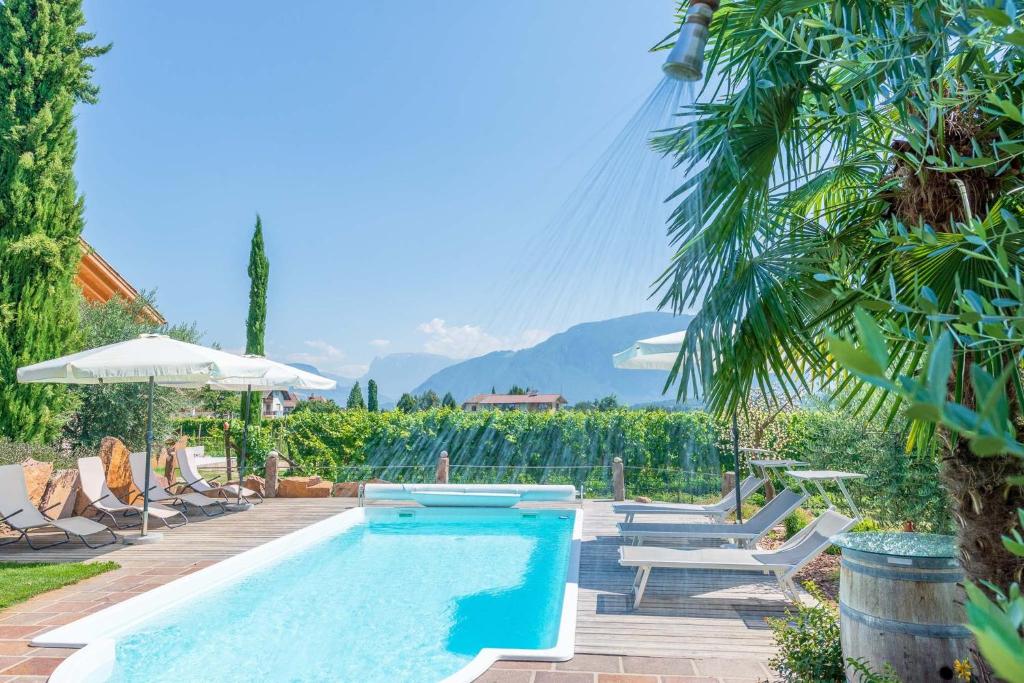 a swimming pool with lounge chairs and an umbrella at Weinangerhof St Pauls in Missiano