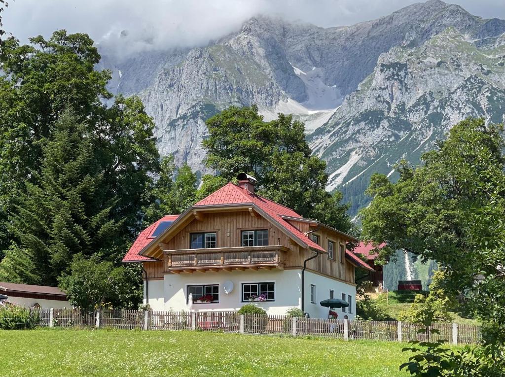 a house with a red roof in front of a mountain at Haus Rosenheim in Ramsau am Dachstein