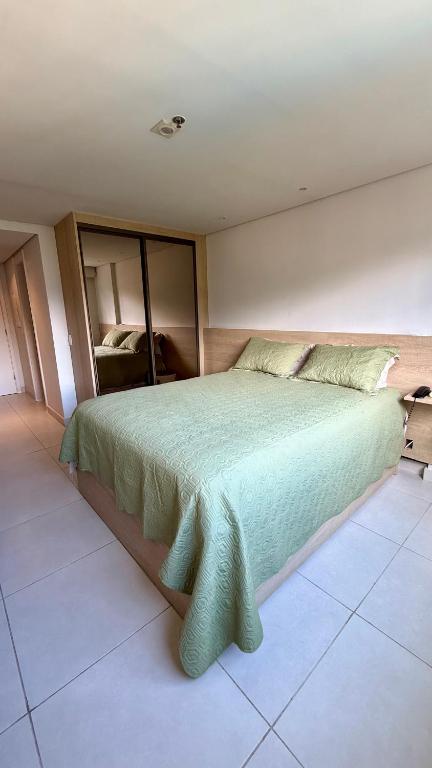 a bedroom with a bed with a green bedspread at Granja Brasil , Studio Itaipava in Araras Petropolis