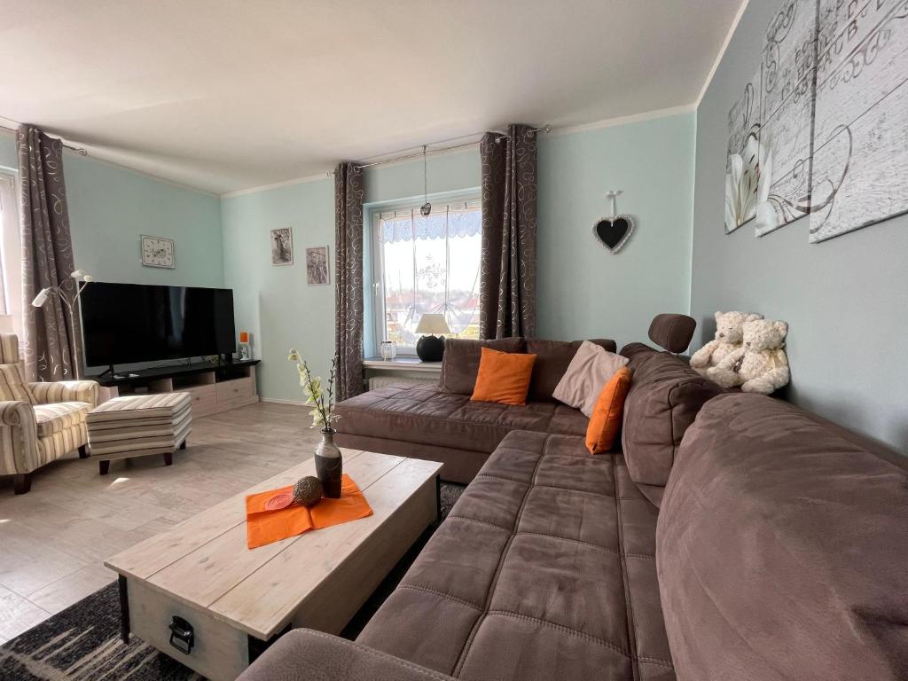 a living room with a brown couch and a tv at Ferienhaus Sweethome - mit Garten in Bad Sachsa