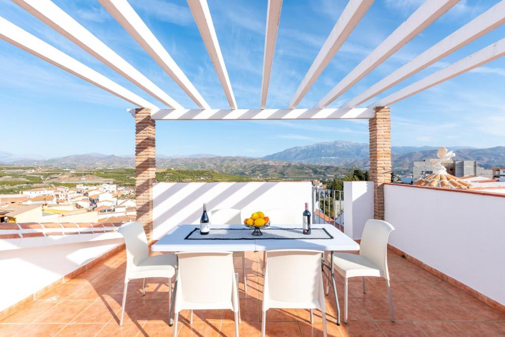 a dining room with a table and chairs on a balcony at Villa Cañete in Benamocarra