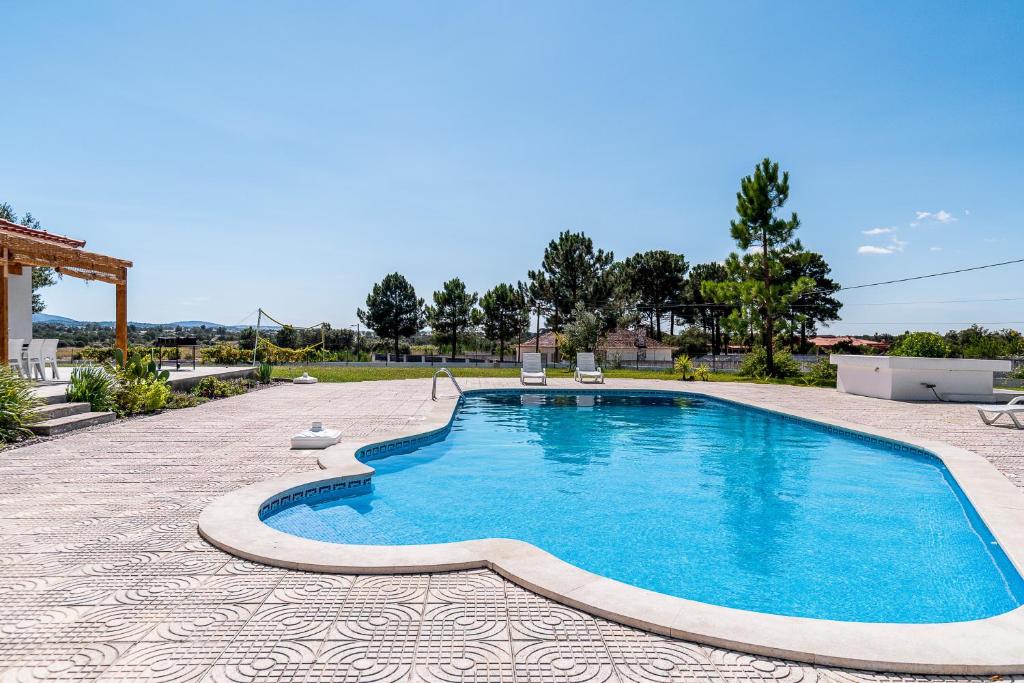 a swimming pool with two chairs in a yard at Palmela Sunset Villa in Quinta do Anjo
