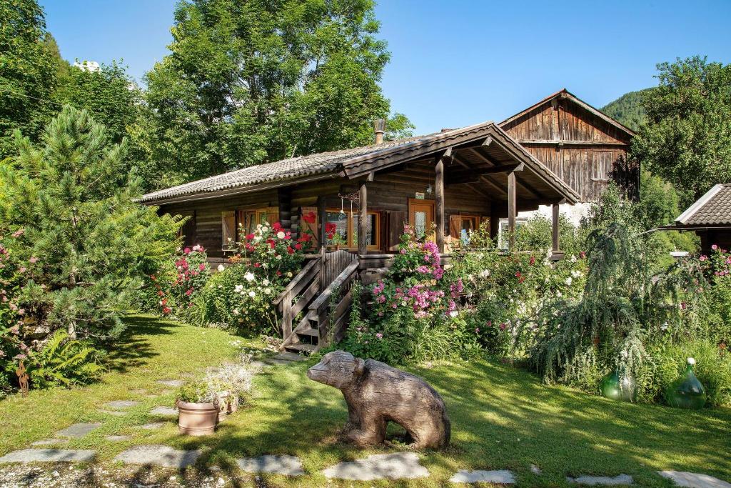 a wooden house with a bear statue in the yard at Orserose Chalet 1 La Bilancia in Forno di Zoldo