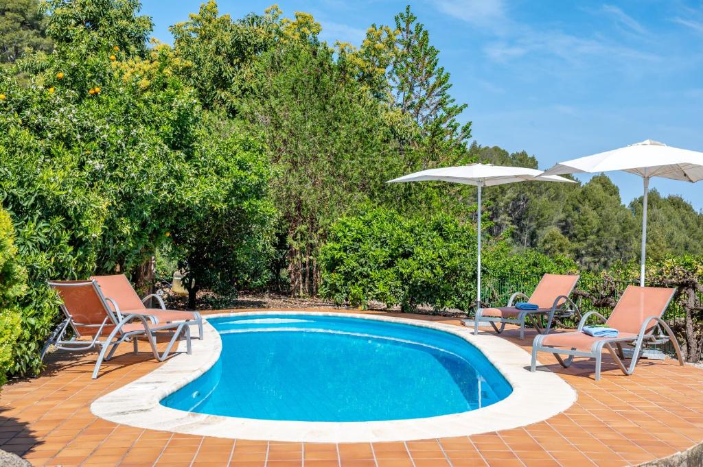 a swimming pool with two chairs and two umbrellas at Can Jaumins in Sóller