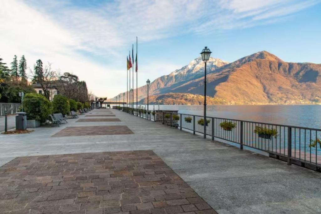 a walkway next to a body of water with mountains at Gravedona Holiday - Lake Como in Consiglio di Rumo
