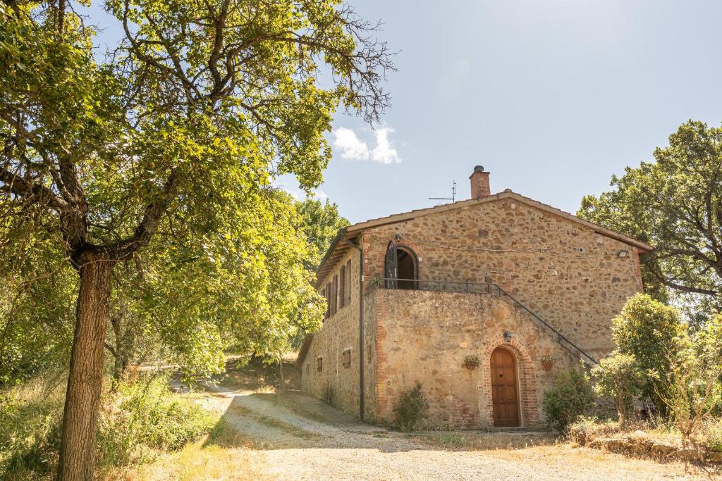 an old brick building with a tree in front of it at Podere Villa Rosa Torrita di Siena in Torrita di Siena