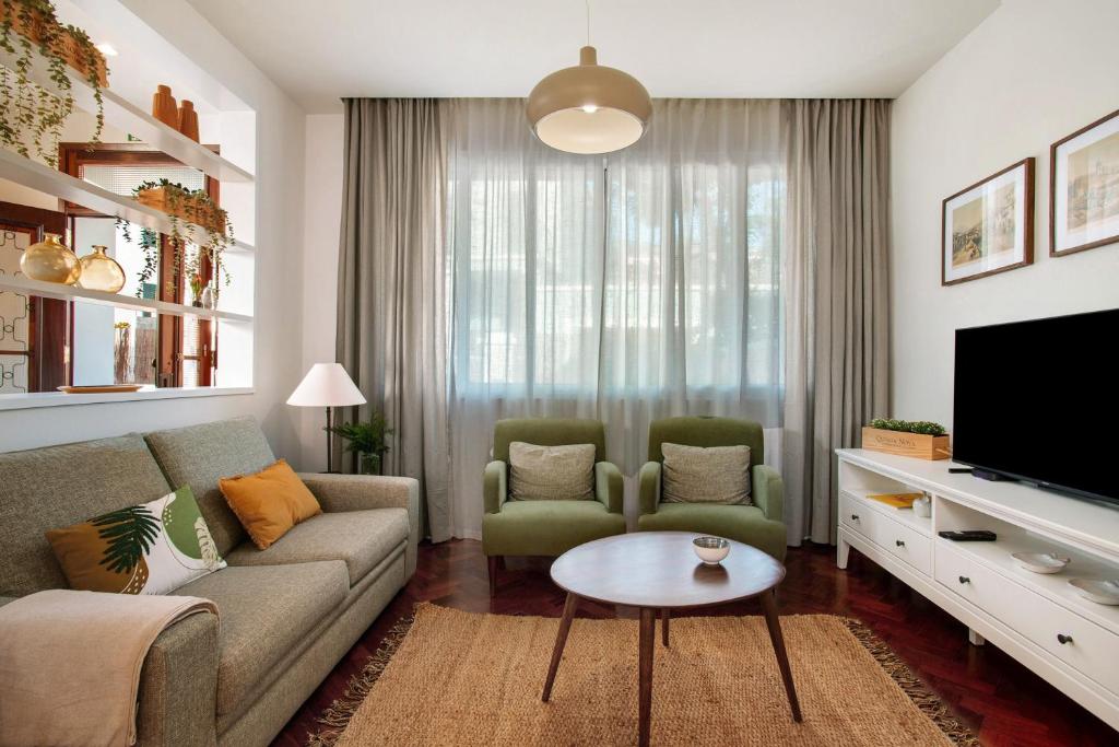 a living room with a couch and two chairs and a tv at Casa do Loureiro in Funchal
