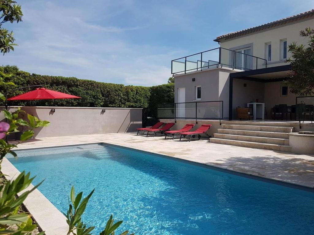 a swimming pool with red chairs and a house at Maison D'hôtes en Drôme Provençale in Vinsobres
