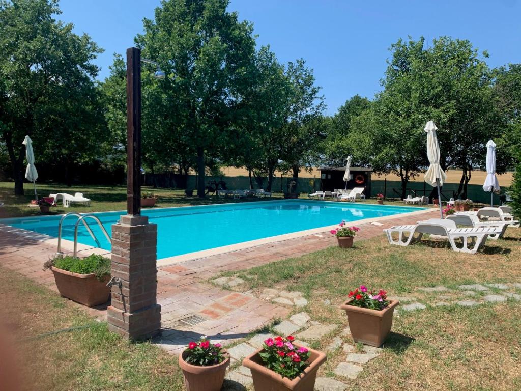 a swimming pool with flowers in pots in a yard at Il Forcone in Panicale