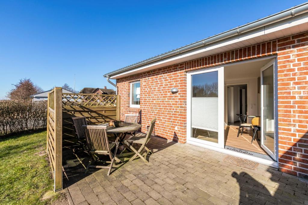 a patio with a table and chairs next to a brick building at Ferienhaus Waterkant mit Hund in Klanxbüll