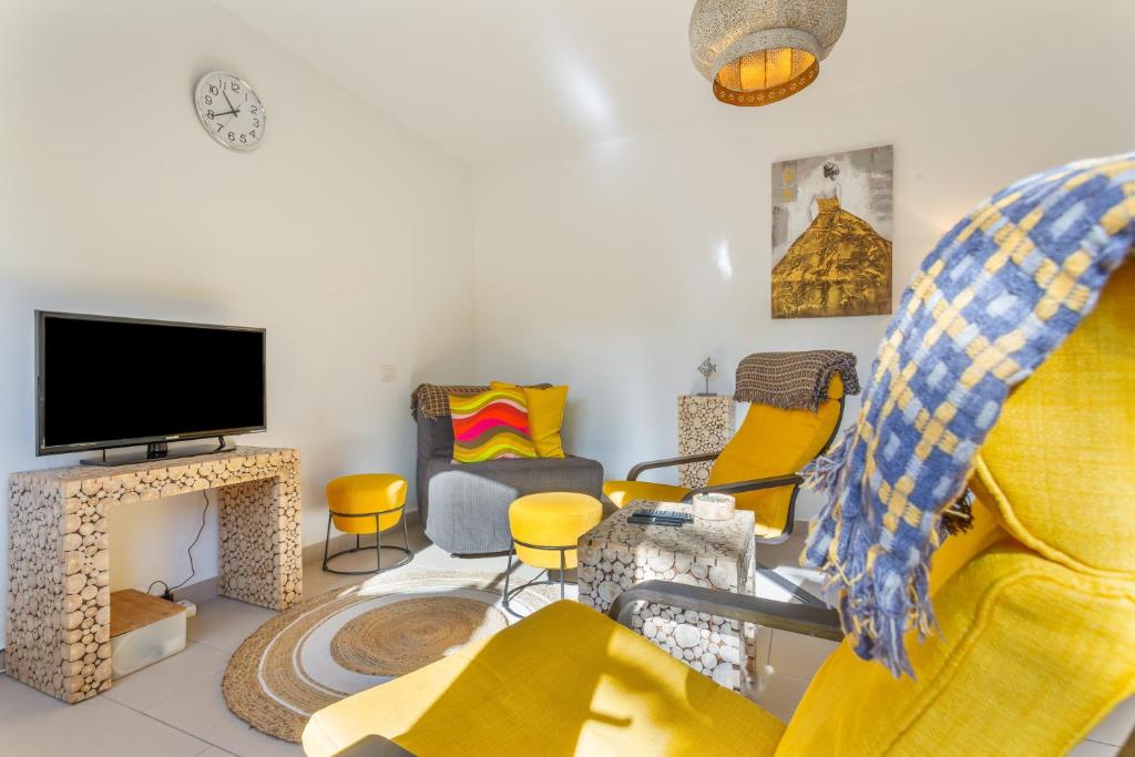 a living room with yellow chairs and a flat screen tv at Casa Alvates in Corralejo