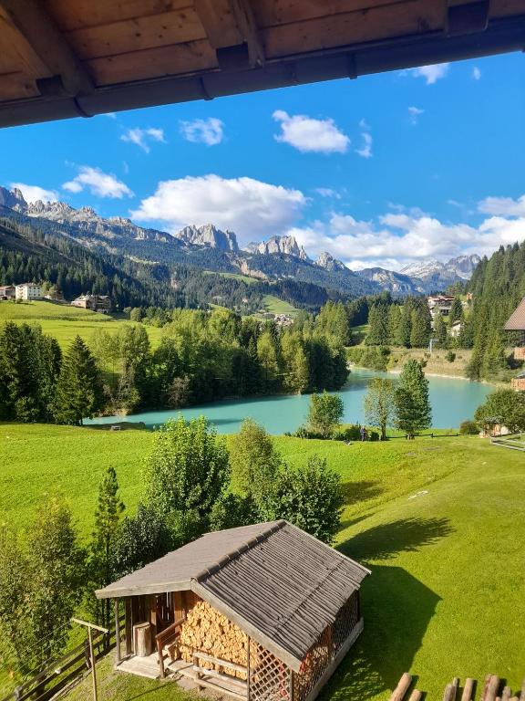 a house in a field with a lake and mountains at Casa Defrancesco - with terrace in Moena