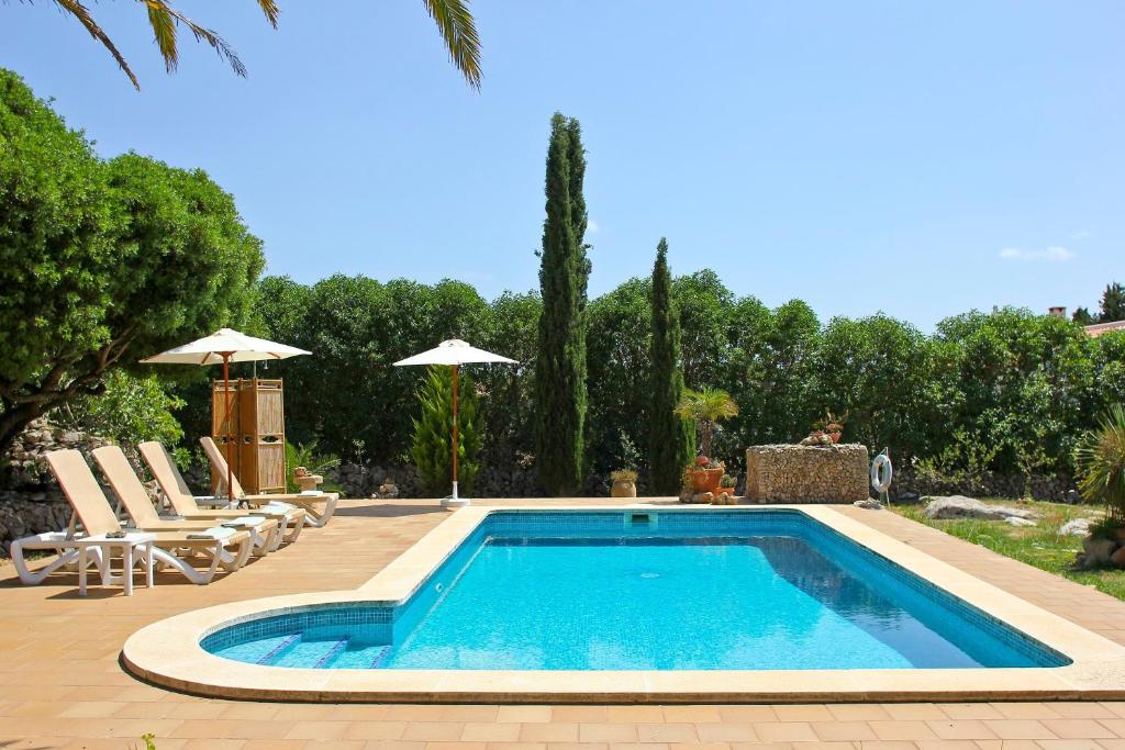 a swimming pool in a yard with chairs and umbrellas at Las Tórtolas in Alaior