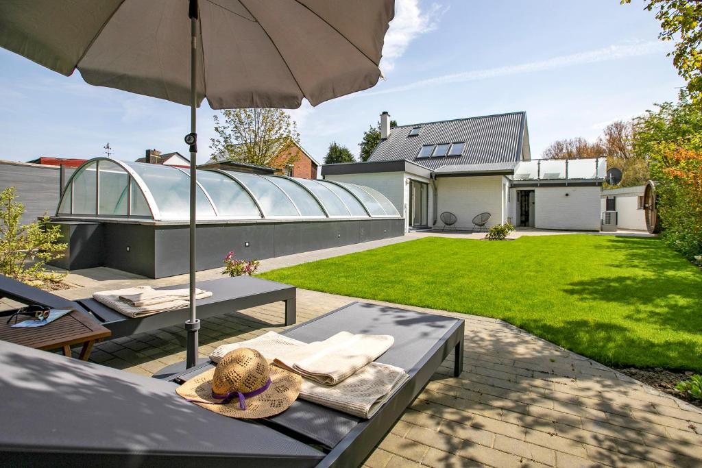 a patio with a table and an umbrella and a yard at Ferienhaus Schleibengel in Maasholm