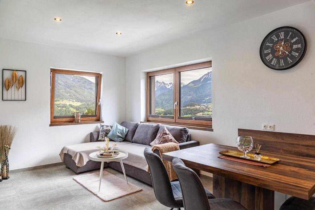 a living room with a couch and a table and a clock at Apart Elias in Gschnallenhof