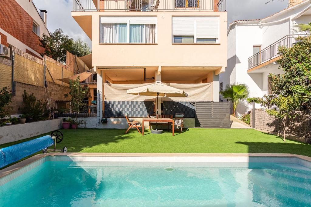 a backyard with a pool and a table and an umbrella at Durero in Pineda de Mar
